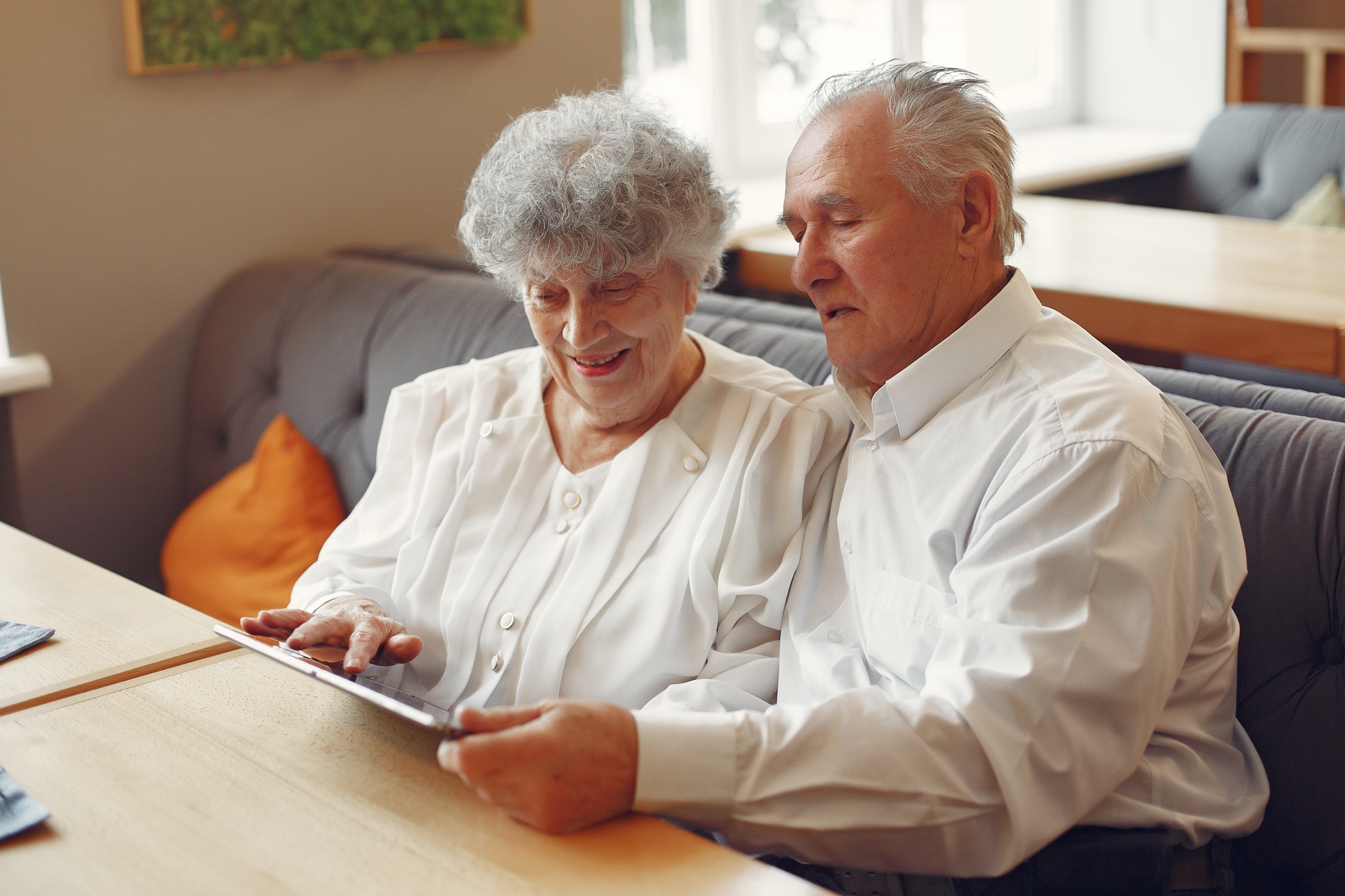 An elegant senior couple at a cafe using a tablet together